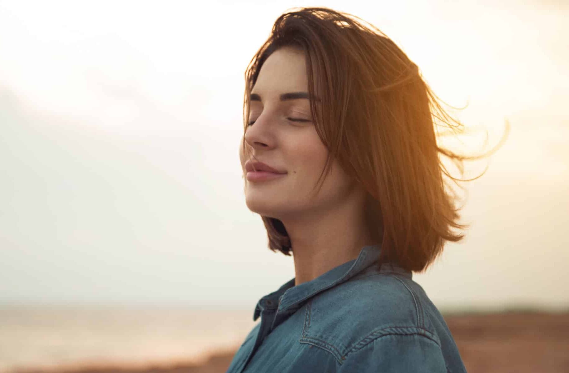 Woman smiling in the wind with beach as a background