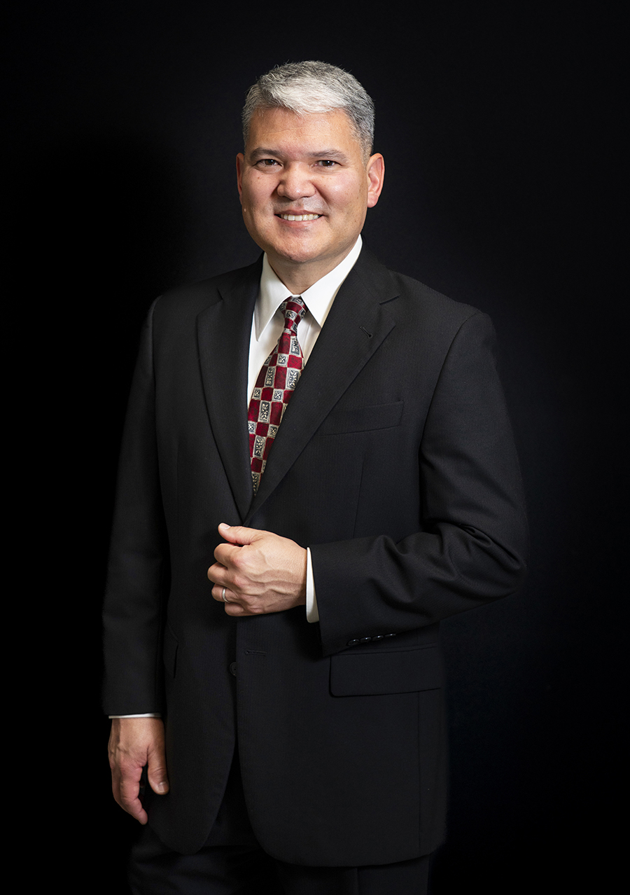 Dr. Chung in a black suit against a black wall